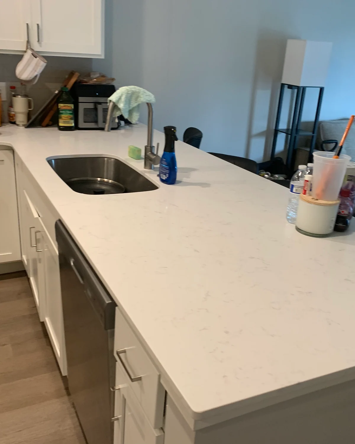 Client-supplied kitchen photo showing an open white countertop and sink with supplies beside the faucet.