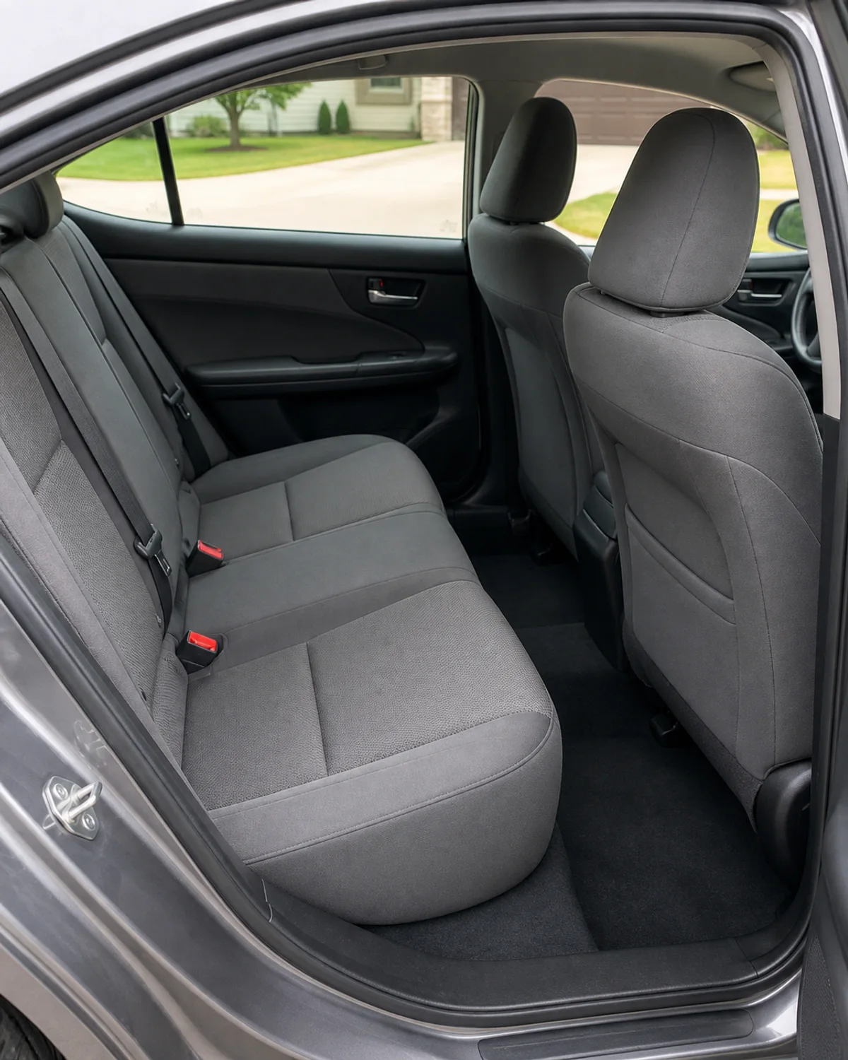 Clean gray cloth rear seats and carpet viewed through an open car door.